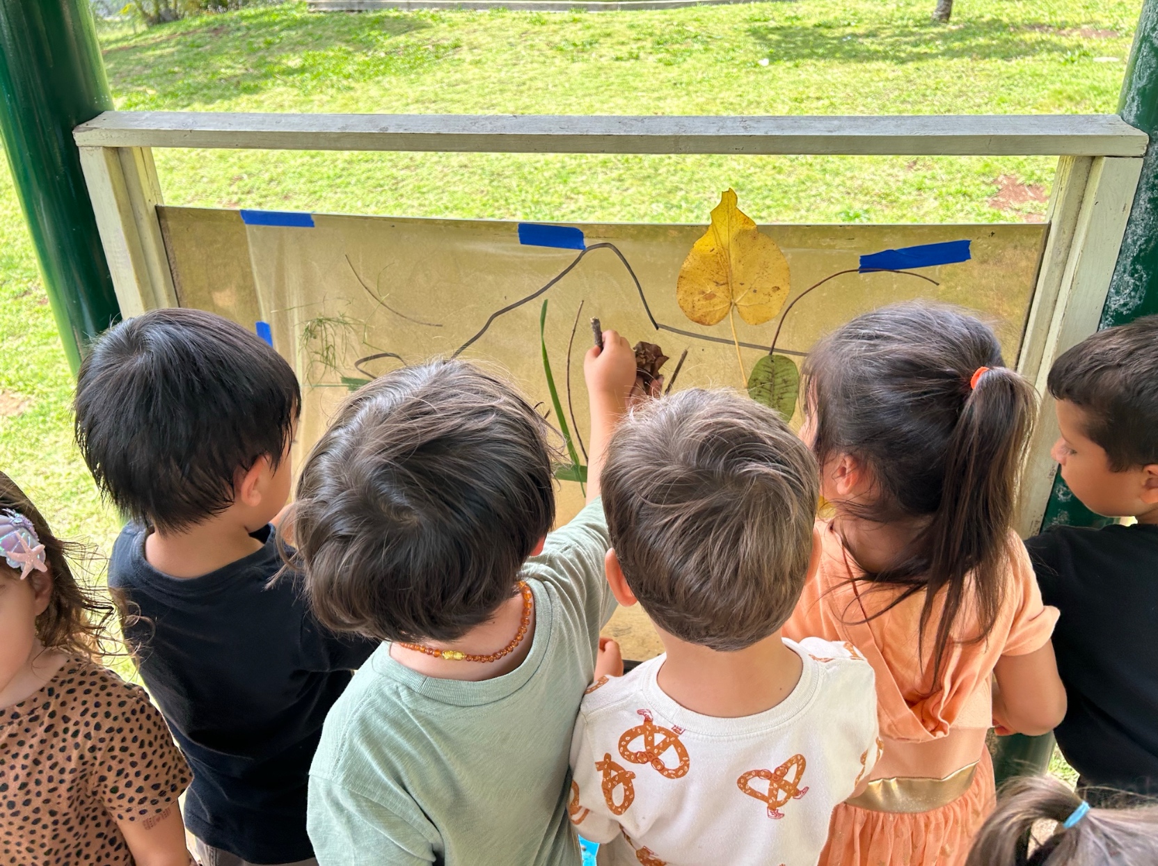 Nature sticky wall — leaves, sticks, grass, and flowers arranged by kids in class